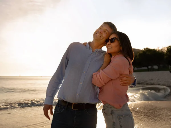 快乐浪漫的中年夫妇享受日落在沙滩上散步 微笑成熟的配偶拥抱和看复印空间 有户外约会 在海上散步时拥抱和拥抱 — 图库照片