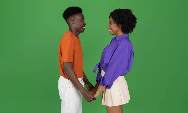快乐的年轻非洲裔美国男人和女人手牵着手 享受着温馨的时光 在绿色的工作室背景下与世隔绝 相貌各异 浪漫的约会 广告和提供 — 图库照片