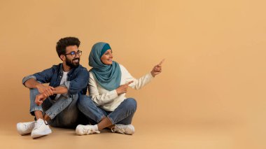 Şuraya bak. Fotokopi çekilen boşluğu işaret eden mutlu Müslüman aile, tesettürdeki neşeli Arap erkek ve kadın reklam için bedava yer gösteriyorlar, bej arka planda oturan İslamcı çift, Panorama