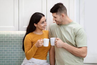 Mutlu, sevgi dolu genç bir çiftin portresi evde sabah kahvesinin tadını çıkarıyor. Mutlu yıllar karı koca, mutfakta kahvaltı edin, sohbet edin, gülümseyin.