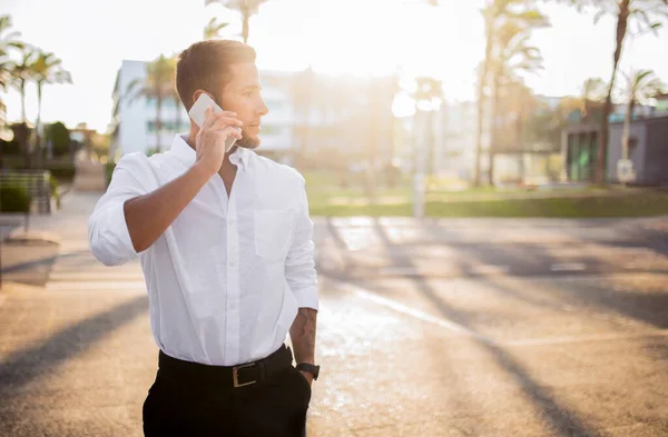 オフィス コピースペースで働く日の後屋外に立って 携帯電話でビジネスコールを持つ正式な衣装で若いヨーロッパのビジネスマンを確信 — ストック写真