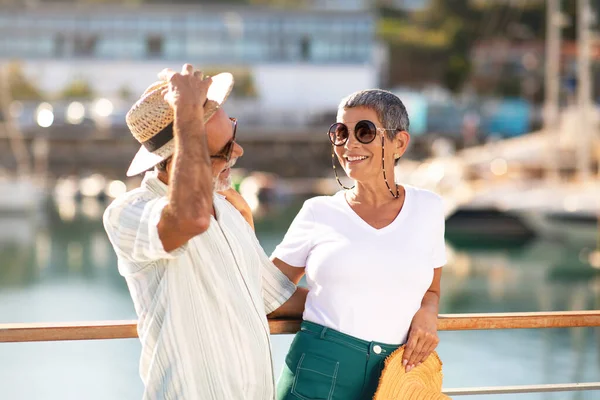 金色的夏天快乐的老人牵着草帽 拥抱着妻子 带着游艇和豪华游艇一起坐船到码头 在户外度假时嬉笑着 嬉戏着享受阳光灿烂的日子 — 图库照片