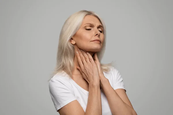 不幸な悲しい病気成熟した女性の肖像画痛み喉 手で首に触れる病気のシニア女性 痛みを感じ 灰色のスタジオの背景に孤立立って コピースペース — ストック写真