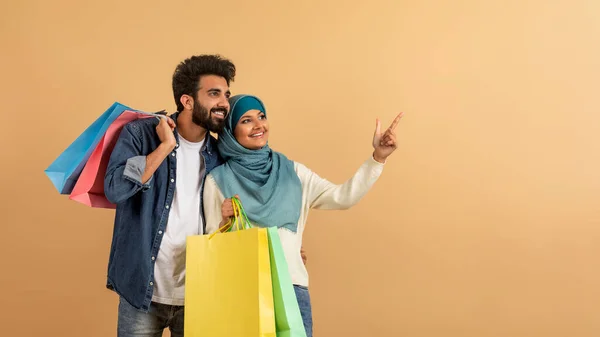 Banner Publicitario Con Feliz Pareja Musulmana Sosteniendo Bolsas Compras Señalando —  Fotos de Stock