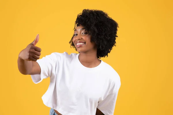 令人高兴的是 千年黑人妇女穿着休闲装展示大拇指向上的手势 被隔离在黄色的工作室背景下 非常接近 人类情感 生活方式 广告和服务 — 图库照片