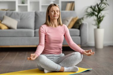 Meditasyon Konsepti. Güzel, sakin bir kadın Lotus pozisyonunda meditasyon yapıyor, huzurlu, genç, beyaz bir kadın yoga yapıyor, ışık odasında gözleri kapalı oturuyor, boşluğu kopyalıyor.