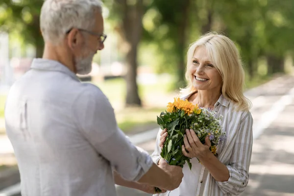 Romantik Olgun Bir Adam Mutlu Karısına Açık Havada Çiçek Veriyor — Stok fotoğraf