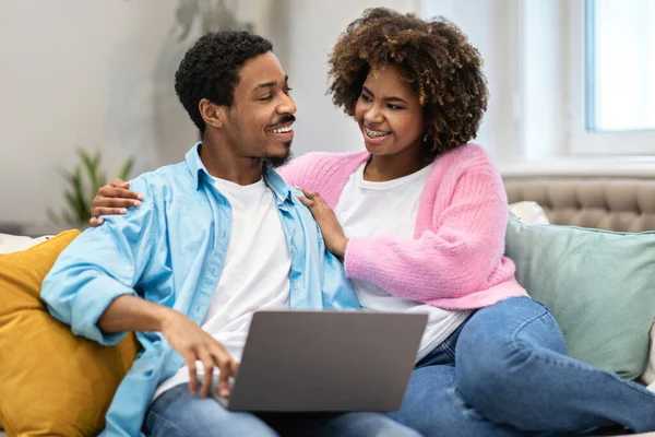 커플은 집에서 인터넷 쇼핑을 즐거운 아프리카 미국인 연인들은 소파에 노트북을 — 스톡 사진