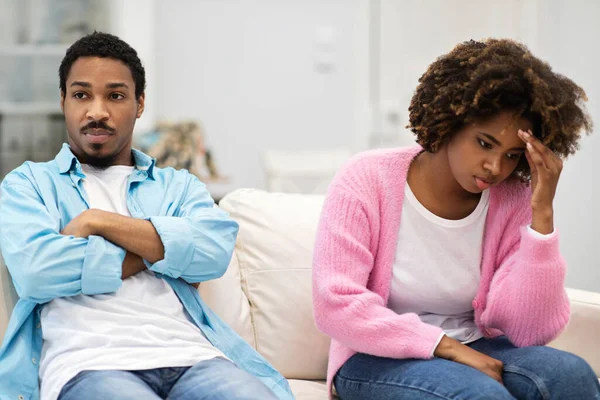 家庭冲突概念 固执的黑人夫妻肩并肩坐在沙发上 避免吵架后说话 生气的男人和女人分别坐在沙发上 彼此不理睬 夫妻不正视对方 — 图库照片