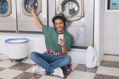 Kulaklıklı Latin Adam, hafta sonları çamaşır makinesinde çamaşır yıkarken, çamaşır yıkarken ve çamaşır yıkarken müzik dinliyor. Ev İşleri Boş Zaman Konsepti