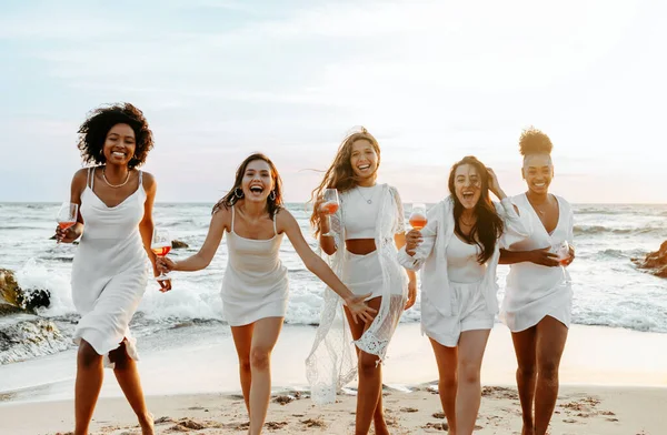 stock image Brides team. Group of happy ladies dancing and having fun on the beach, having hen party at coastline. Female friends enjoying their vacation on ocean shore