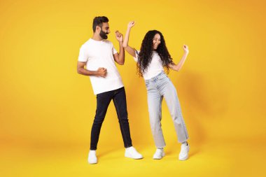 Harika bir teklif reklamı. Sarı Stüdyo 'nun arka planında iyi haber pozunu kutlamak için dans eden ve yumruklarını sallayan neşeli bir Arap çift. Neşeli Eşlerin Tam Uzunluğu Neşeli İfade Ediyor. Kutlama Kavramı