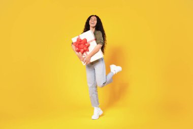 İyi ki Arap Kadın Paketli Doğum Günü Hediye Kutusu Stüdyoda Sarı Arkaplanda Duran Kamera Pozuna Gülümsüyor. Sunar Teslimat, Tatil Kutlama Konsepti. Tam Uzunluk