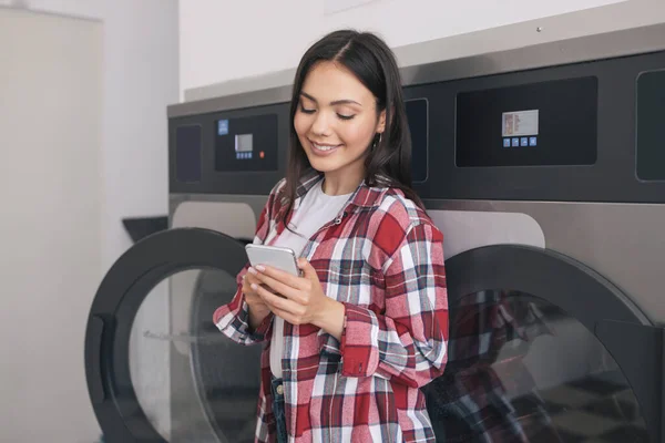 Happy Student Woman Doing Laundry Texting Cellphone Booking Laundromat App — Stok Foto