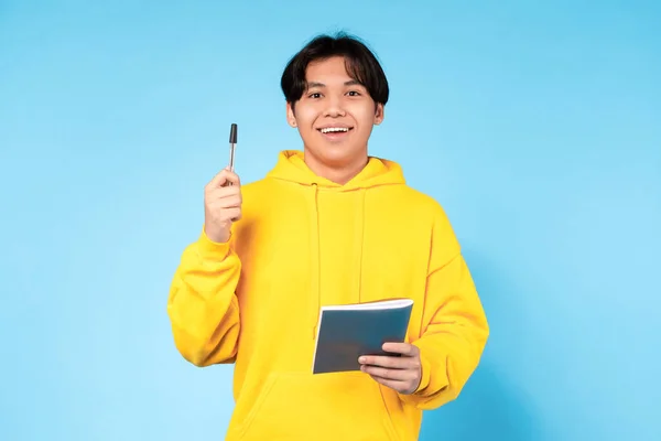 素晴らしいアイデア インスピレーション 明るいアジアの学生の男の肖像がペンアップと笑顔を調達 すごい創造的なアイデアを持っています 青いスタジオの背景の上に立って ユーレカ モーメント コンセプト — ストック写真