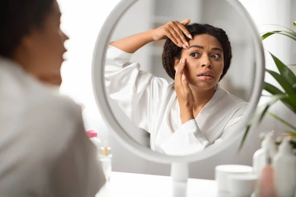 自宅で美容ルーチンを作りながら 彼女の目の周りにしわをチェック若い黒人女性を動揺 鏡と感動的な顔を見て美しいアフリカ系アメリカ人女性 ストレスを感じます 選択的な焦点 — ストック写真