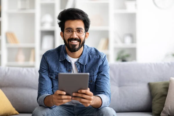 Yakışıklı Hintli Adam Dijital Tablet Bilgisayar Tutuyor Kameraya Gülümsüyor Koltukta — Stok fotoğraf