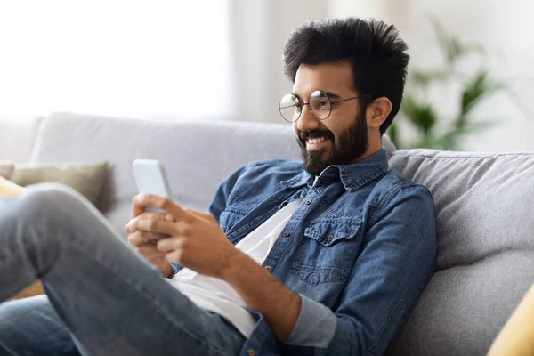 Dating App Fröhlicher Junger Indischer Mann Entspannt Mit Smartphone Hause — Stockfoto