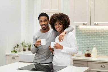 Sevimli, sevecen, siyah erkek ve kadın pijamalarıyla masanın başında duruyor, kameraya sarılıyor ve gülümsüyor, sabahın köründe birlikte kahve içiyor, mekanı kopyalıyor.