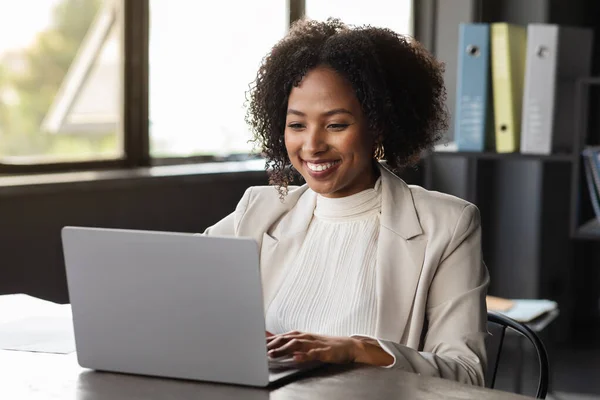 現代のオフィスでラップトップで働いている白い正式な衣装マネージャで陽気な笑顔かなり若い黒人女性 ビジネス女性は クライアントとチャット 電子メールに応答 コンピュータを使用して スペースをコピー — ストック写真