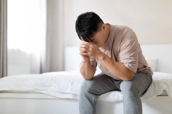 忧心忡忡的中年英俊亚裔男子身穿睡衣 独自坐在床上 患有忧郁症 孤独或焦虑 复制空间 中年危机 — 图库照片