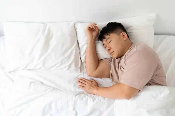 彼の巨大な快適なベッド 彼の隣の空のスペースで一人でパジャマ睡眠を着て平和なハンサムな中年アジアの男性のトップビュー 一人暮らしをコンセプトに — ストック写真