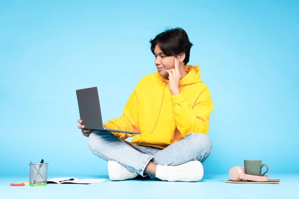 Eラーニング レジャー ノートパソコンを使った日本人学生が自宅で仕事をしたり ブルースタジオを背景に床に座ってオンラインでビデオ通話をする インターネットと教育 — ストック写真