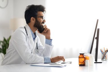 Klinikte çalışan bin yıllık yakışıklı Arap doktor, çalışma masasında çalışan pratisyen hekim, bilgisayar bilgisayarı kullanan, hasta ya da meslektaşıyla telefon görüşmesi yapan, yan görüş