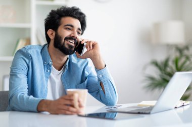 İş molası. İçişleri Bakanlığı 'nda masasında dinlenen, gülümseyen, cep telefonuyla konuşan, kahve içen, cep telefonuyla konuşan, sıcak içeceklerin keyfini çıkaran,