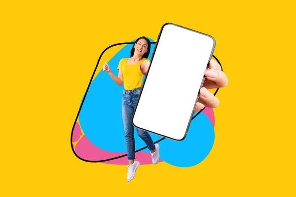明るい色のスプラッシュ コラージュ モックアップで黄色の背景に楽しさを持っている巨乳の若い女性が手に大きな空白のスマートフォンでジャンプし 親指を表示します — ストック写真