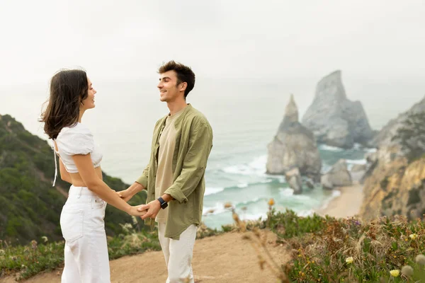 ビーチサイド ボンディング ロマンチックなデートを持つ愛の若いヨーロッパのカップル 手を取り合い お互いを見て 美しい景色と海岸線に立って フリースペース — ストック写真