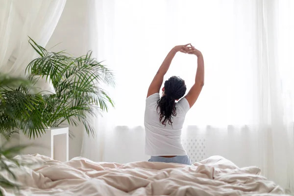 Young Black Woman Sitting Bed Stretching Arms Waking Rear View — Stock Photo, Image