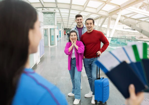 Travel Agent Lady Showing Boarding Passes Tickets To Joyful Tourists Trio Standing With Suitcase At Airport Indoor. Selective Focus On Group Of Excited Passengers. Wow Offer, Transportation