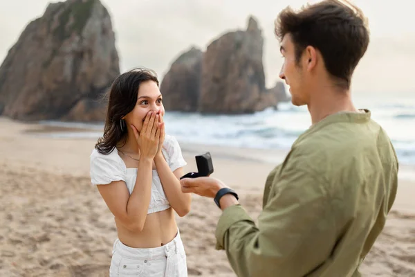 在海滩上与年轻人和女士在结婚戒指上的惊喜和订婚 把送给女人的日期 礼物和钻石戒指都省下来 让她们浪漫一下 — 图库照片