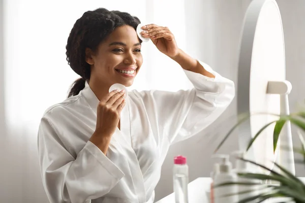 使用棉垫的黑人微笑女人 在家里用胶水洗脸 迷人的非洲裔美国女性对皮肤的呵护 享受日常面部皮肤护理 — 图库照片