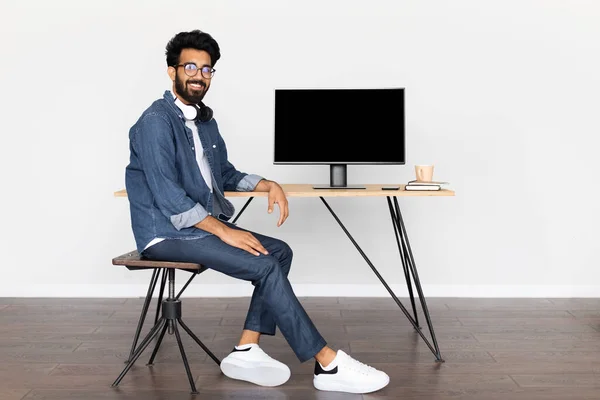 身穿休闲装的年轻英俊的中东男子 面带微笑地坐在办公桌前 电脑上有黑色的空屏幕 从总部上网工作的阿拉伯人 复制空间 — 图库照片