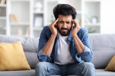 Evde migrenden muzdarip genç Hintli bir adamın portresi. Doğulu adam kendini kötü hissediyor. Kapalı gözlerle şakaklarına dokunuyor, koltukta otururken şiddetli baş ağrısı çekiyor.