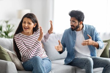 Kızgın, genç, doğulu bir erkek tacizci duygusal ağlayan karısına ya da kız arkadaşına bağırıyor, çift kanepede oturuyor, bağırıyor ve el kol hareketi yapıyor, kavga ediyor, ilişkilerde yanlış anlaşılıyor. ev içi