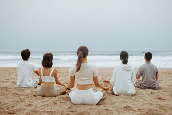 户外瑜伽和冥想课 一群年轻男女在海滩上做呼吸练习 在海滨享受早上的训练 — 图库照片