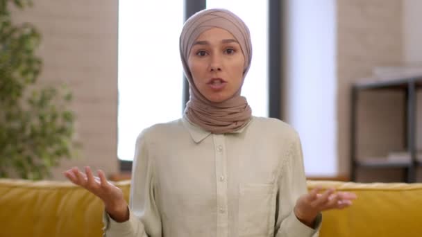 照片中 年轻的情绪激动的穆斯林女性影响者身穿传统的头巾 在家里录制视频博客 与订户交谈 — 图库视频影像