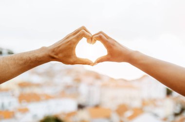 Genç Afrikalı Amerikalı erkek ve bayanın elleri kalp işareti yapar, buluşmanın tadını çıkarır, aşk hikayesi ve seyahat, açık havada. İlişkiler, tatil, tatiller ve romantizm, evlilik ve nişan