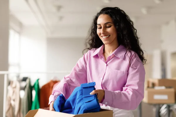 Small Retail Business. Clothing Designer Woman Packing Fashionable Clothes for Delivery In Carton Box In Showroom Indoors. Boutique Owner, Successful Entrepreneurship Concept