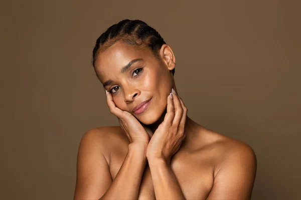 アンチエイジングスキンケアコンセプト 美しいです黒中年女性とともに完璧な肌のタッチ顔と見てカメラ 高齢者の女性立ち上の茶色のスタジオの背景 — ストック写真