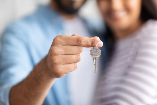Unrecognizable young couple at new home hold house keys moving in together, loving caring husband and wife apartment owners excited relocating to own dwelling, renting, relocation concept