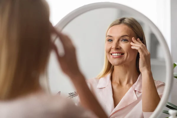 Donna Matura Allegra Guardando Specchio Casa Applicando Crema Gli Occhi — Foto Stock