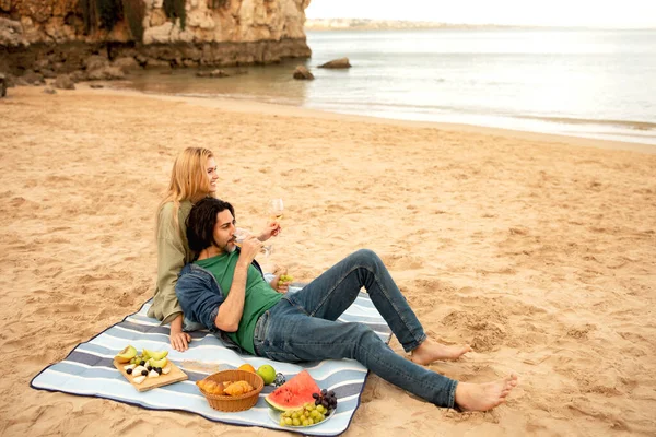 浪漫的年轻夫妇在海滩上野餐 爱快乐的千年男人和女人在海滨喝酒放松 坐在毛毯上享受户外约会 复印空间 — 图库照片