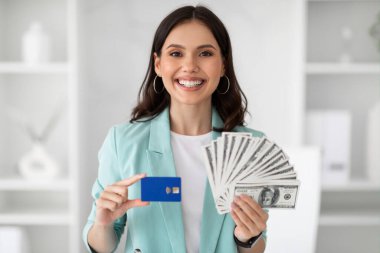 Takım elbiseli genç Avrupalı kadının kredi kartı ve çok para gösterip modern ofis içinde zaferin tadını çıkarmasına sevindim. İş kadını ve başarılı iş, iş ve kazanç, kar, finans