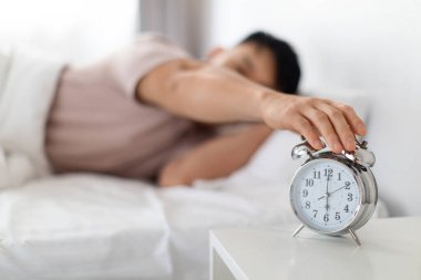 Uyan, günaydın. Pijama giyen Asyalı bir adam çalar saati kapatıyor. Komodinin üzerinde duruyor. Sabah uyandığında saate odaklanıyor, geçmişi bulanık.