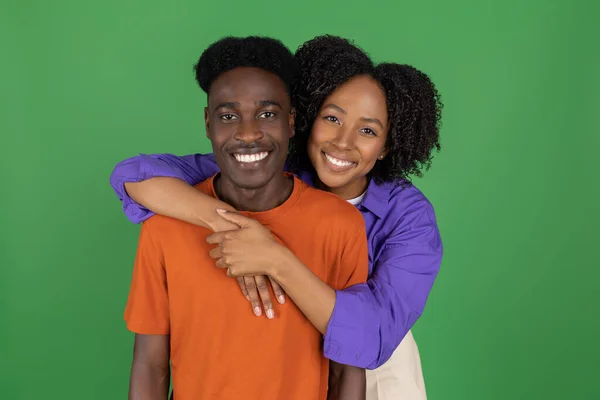 快乐的千年非洲裔美国女士在随意拥抱男友 享受约会 在绿色工作室背景下被隔离 浪漫和欢乐在一起 人的情感 广告和提供 — 图库照片