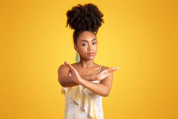 悲伤而自信的年轻黑人女人交叉着胳膊 做了个停车标志 在黄色的背景下被隔离在工作室里 个人空间姿态 反对性别歧视的抗议 广告和提供服务 — 图库照片